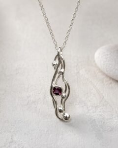 Sculptural silver pendant with deep red garnet gemstone, handmade by Cornovii Silver in Cornwall.