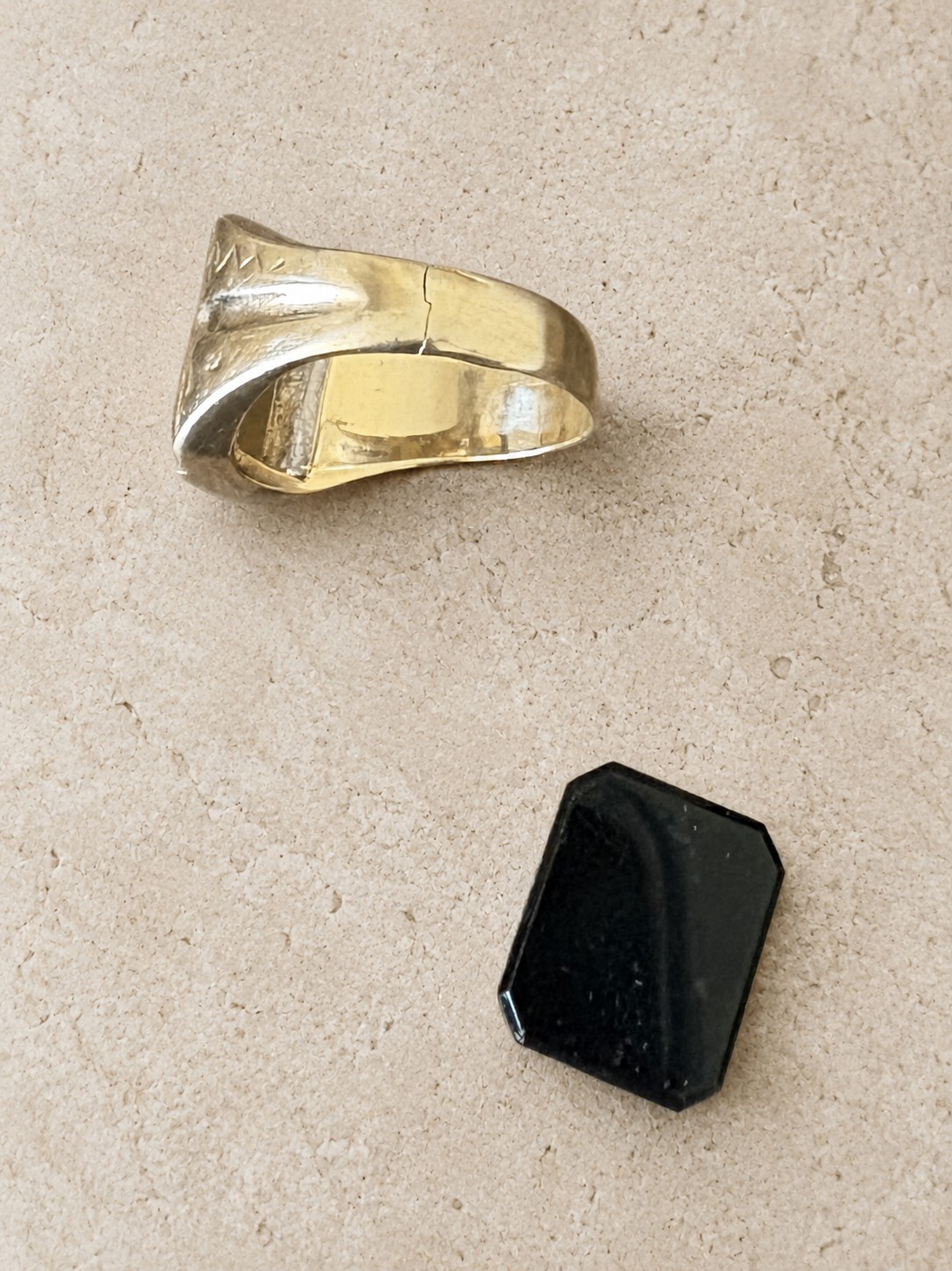 Cracked gold ring with loose black stone before repair.