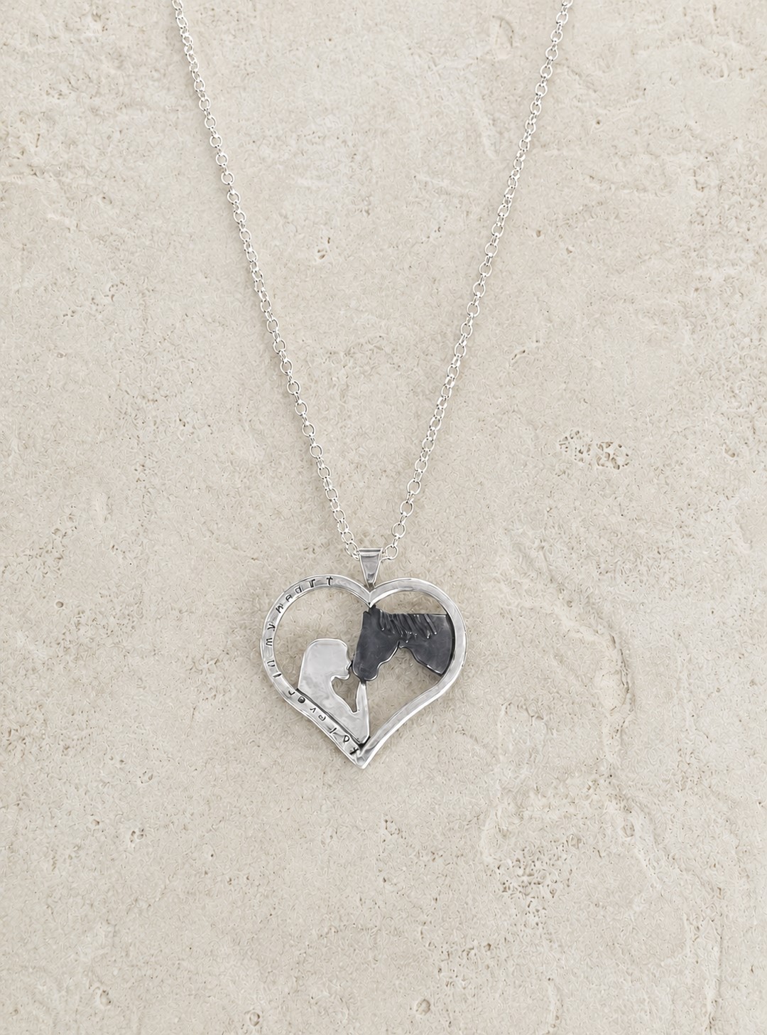 Silver memorial heart pendant featuring a woman and horse design created from a photograph.